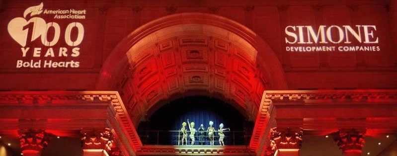 Performers on balcony with projection of american heart association 100 years bold heart logo and Simone logo